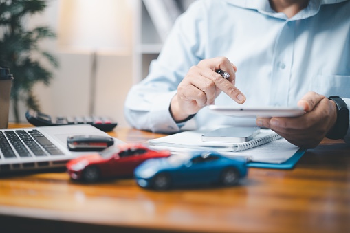A financial analyst at the desk is calculating a title loan for a leased vehicle