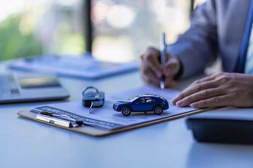 Man is signing paper for pink slip loan for a car