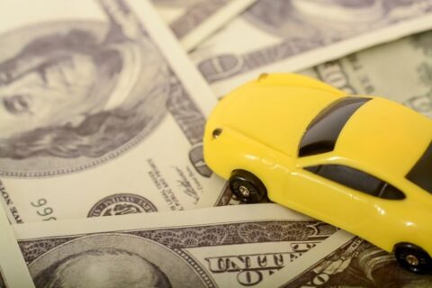 A yellow toy car rests on a stack of cash in the DFW Metroplex