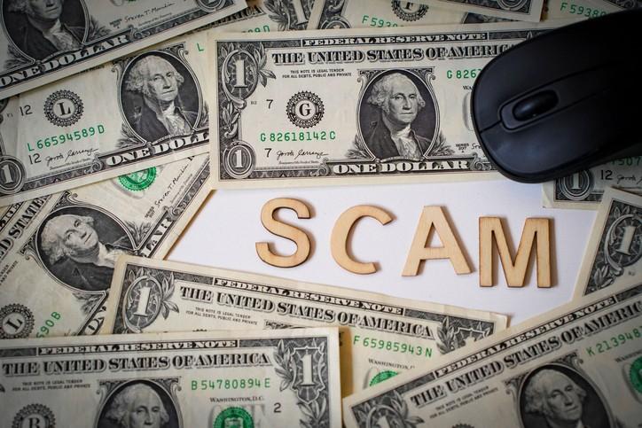 The word scam displayed on cash, accompanied by a mouse and online financial risks in DFW Metroplex