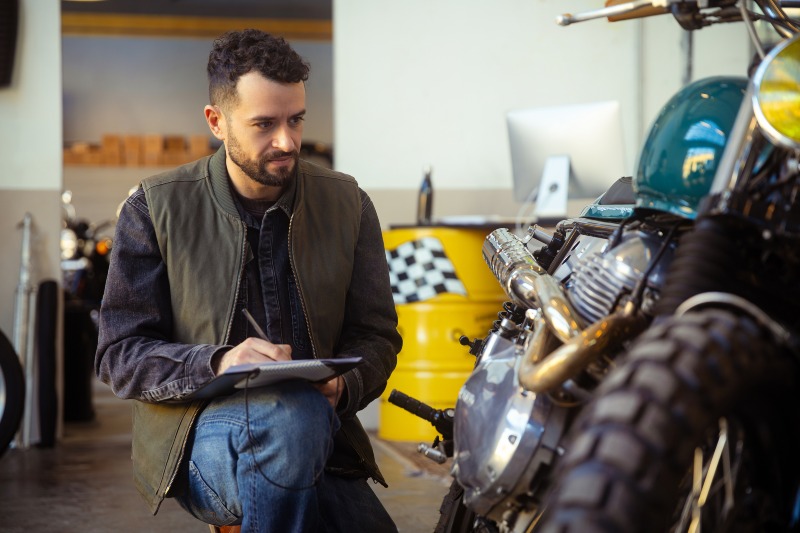 A lender writes on a clipboard, assessing Motorcycle Equity for Title Loans in the DFW Metroplex